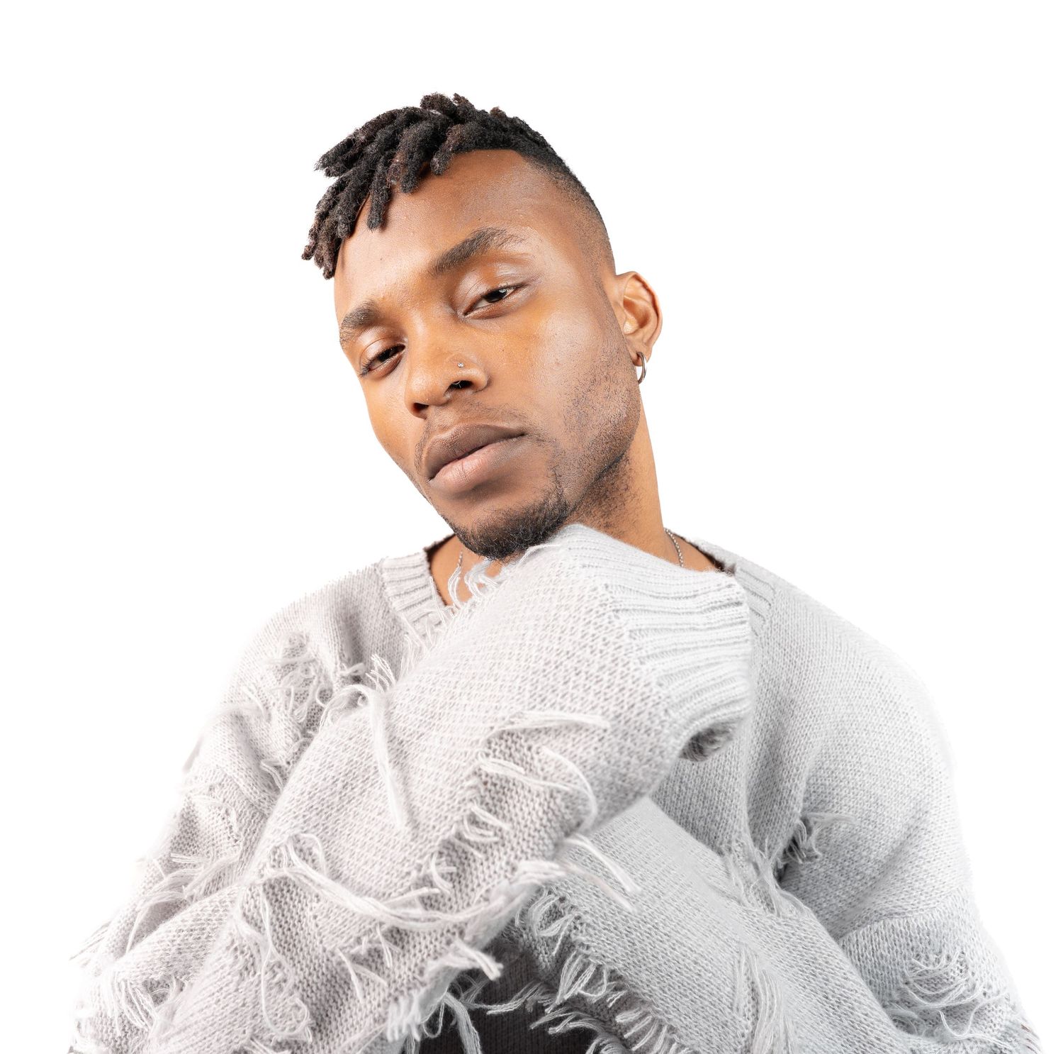 Person in a white textured sweater posing against white background with stylish haircut and earring.