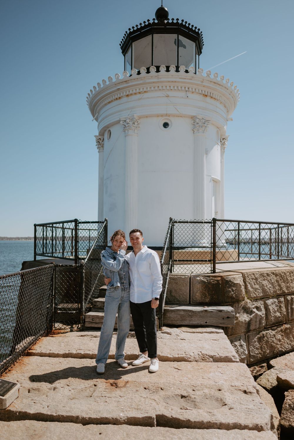 Historic white lighthouse tower with ornate details against blue sky.