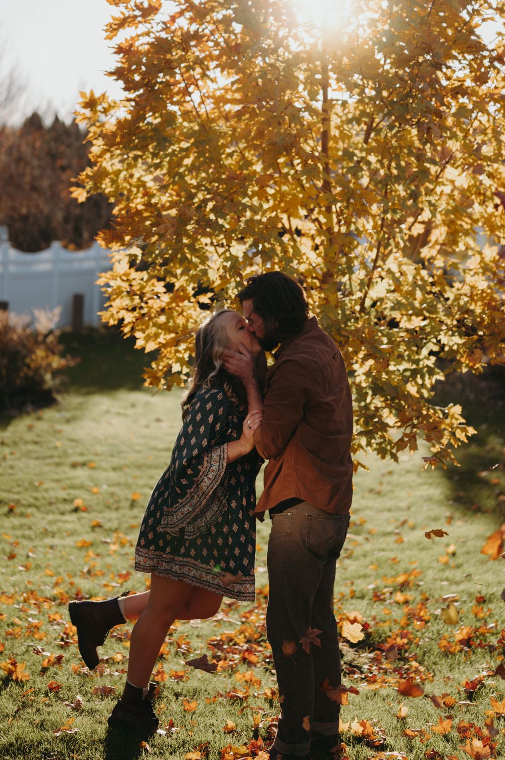 Romantic moment shared between two people in a fall garden with golden sunlight filtering through trees.