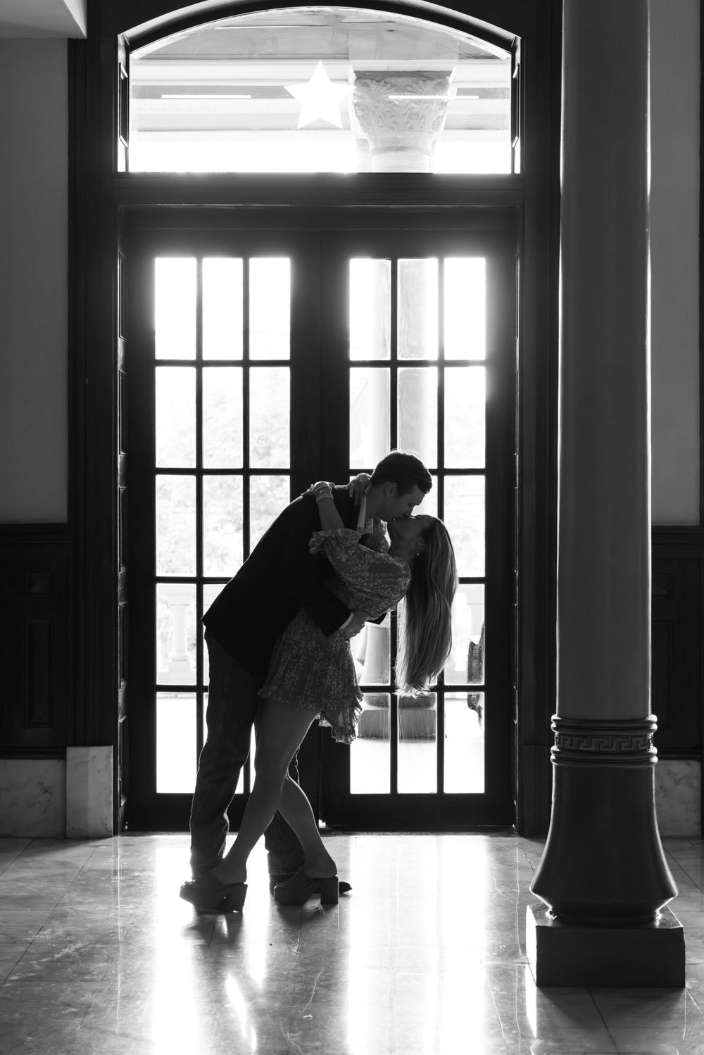 Silhouette of a romantic couple dancing in front of glass doors.