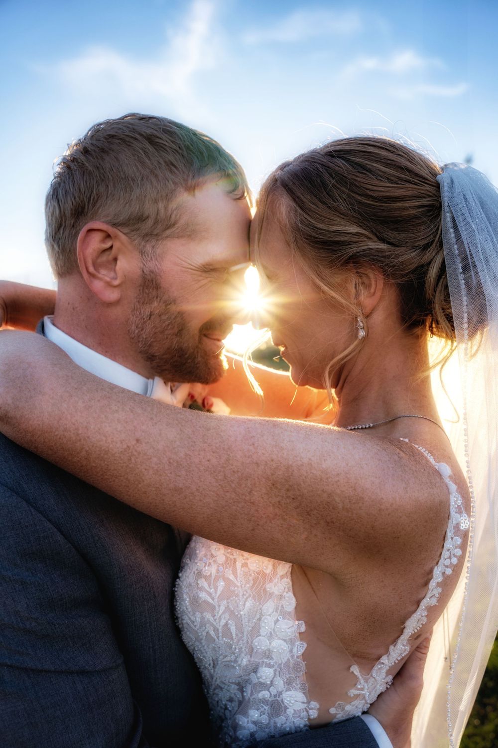 Intimate sunset moment with sunburst between newlyweds.