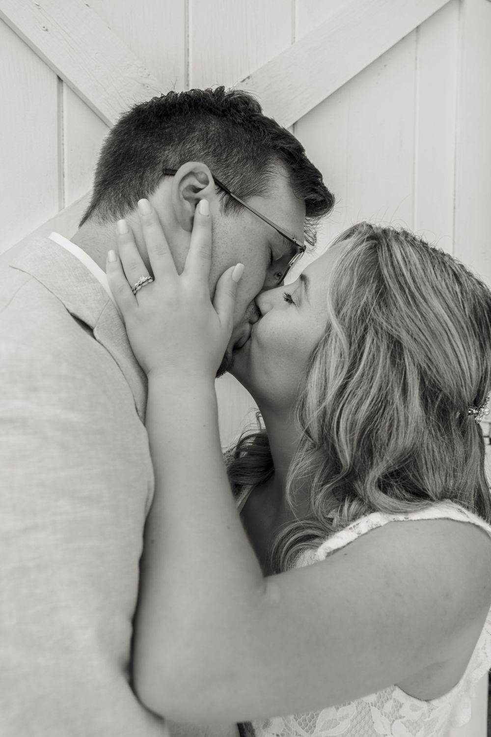 Black and white intimate wedding portrait against white barn door background.