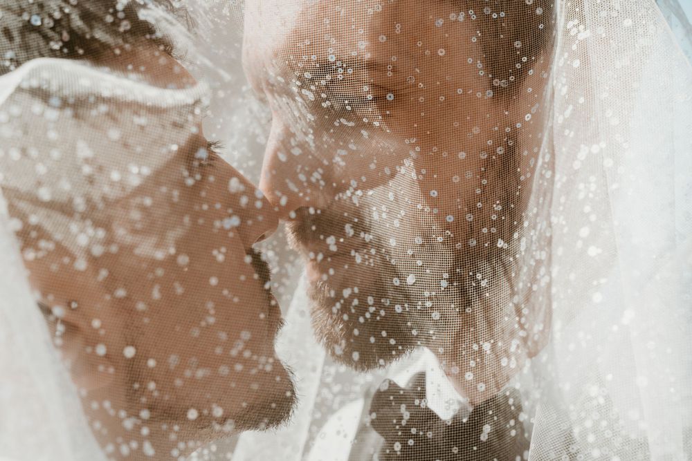 An intimate wedding photograph through sheer fabric creates a dreamy, romantic effect.