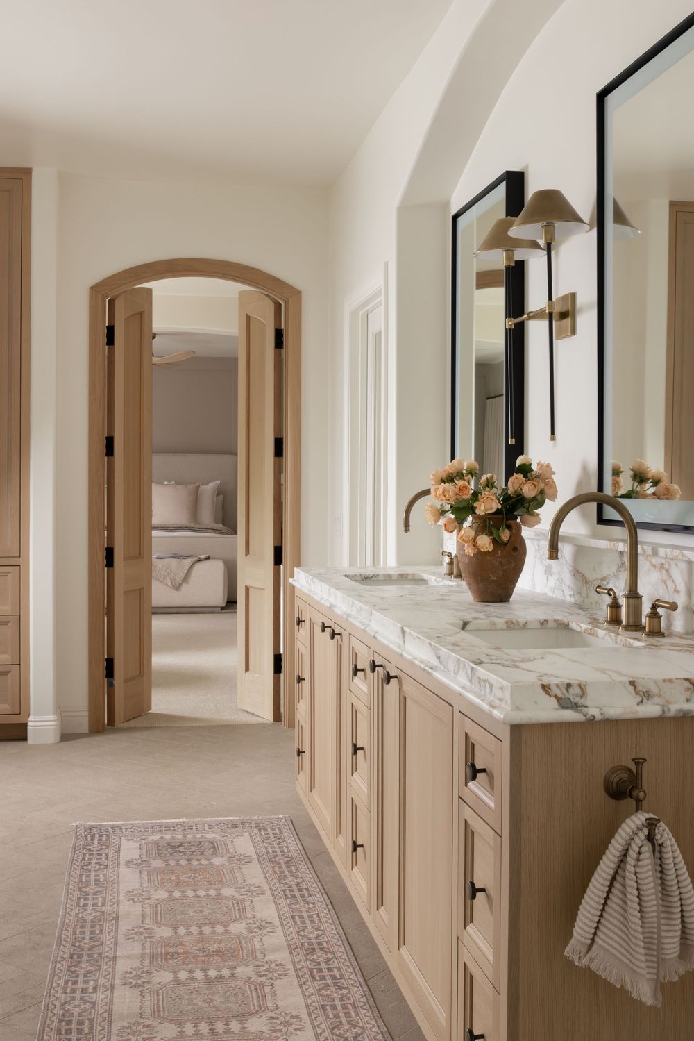 Elegant cream-colored hallway with arched doorways, marble countertops, and a patterned runner carpet leading down the corridor.