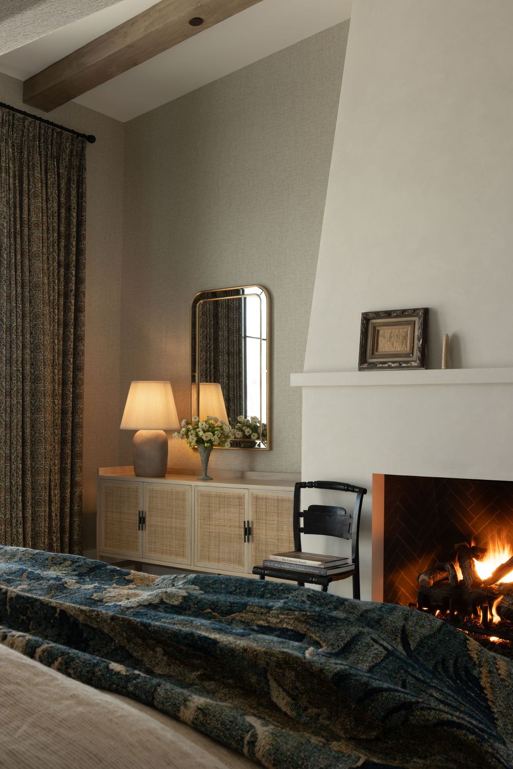 Cozy bedroom interior with fireplace, table lamp, and blue bedding showing different angles of the same space.