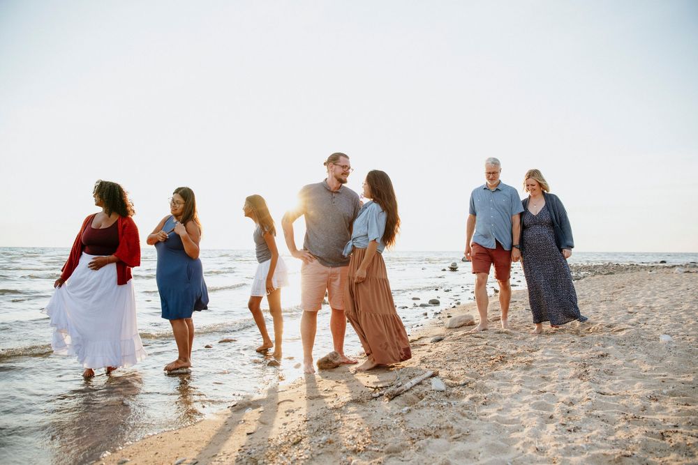 A family walking along a sandy beach at sunset with waves rolling in Charlevoix at Mount McSauba