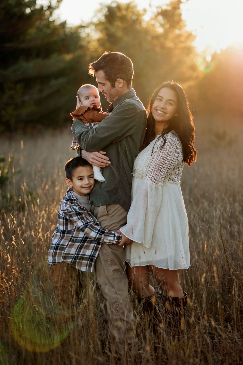 Candid family moment captured in tall grass during golden hour.