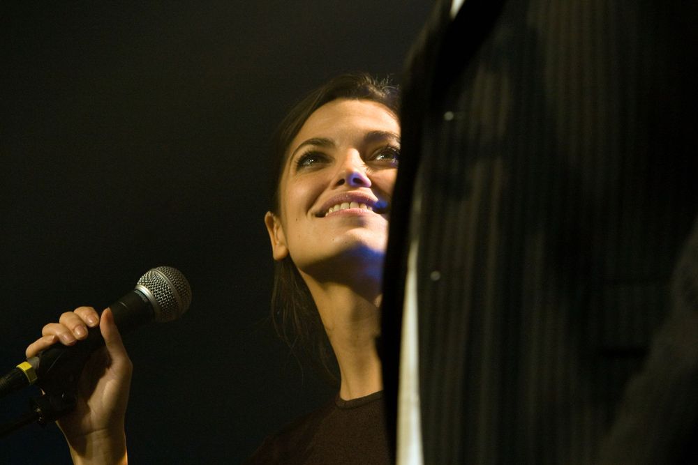 Stage performer singing into microphone with dramatic lighting effects.