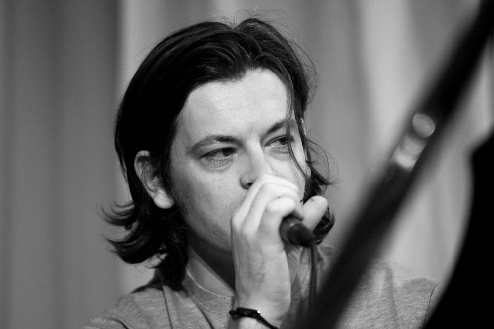 Singer performing emotionally on stage in black and white dramatic lighting during live concert performance.