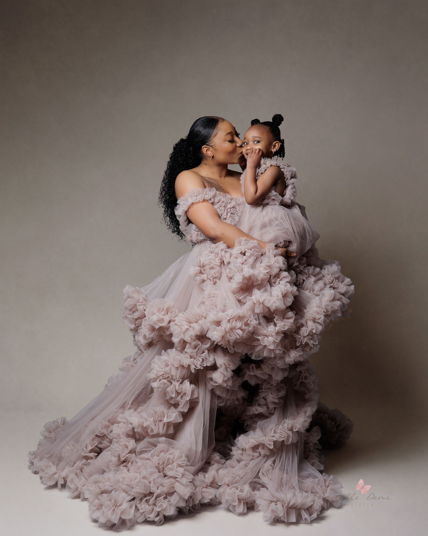 Mother and child wearing matching lavender tulle gowns in a romantic studio portrait.