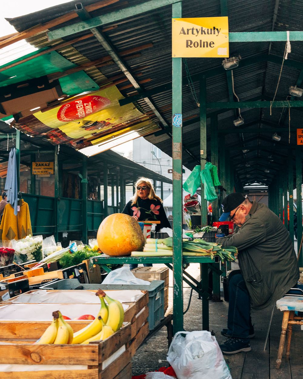 Vendors selling fresh produce and goods at covered outdoor market stalls.
