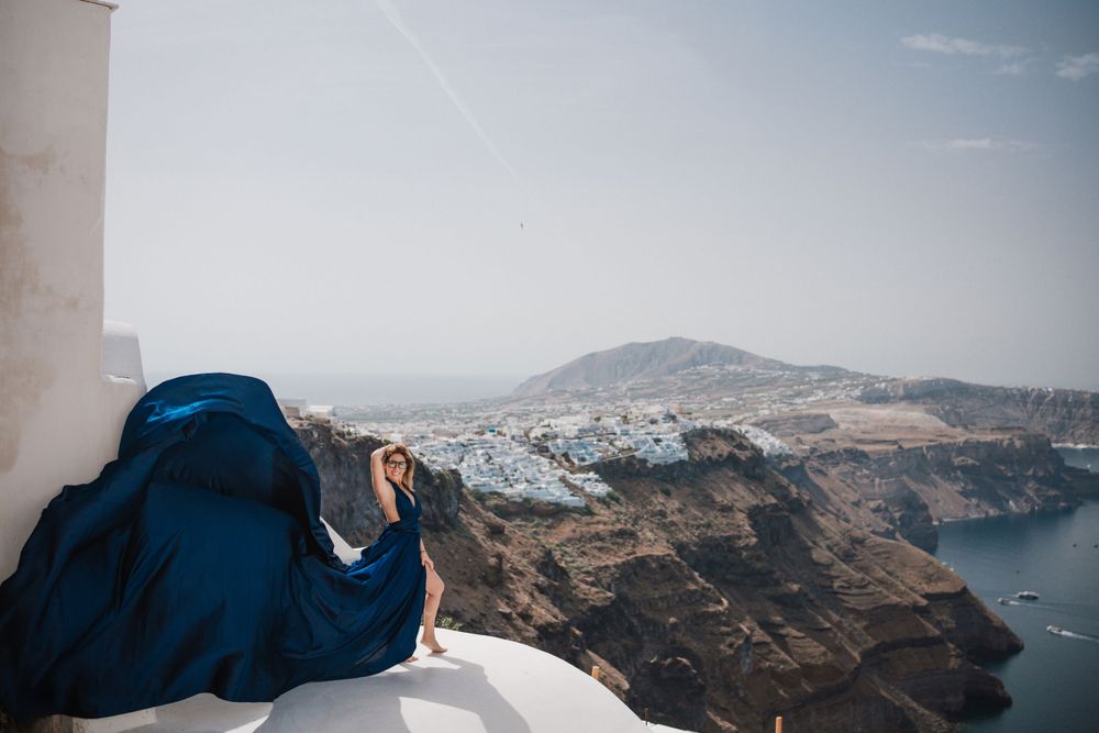 Panoramic view of Santorini's caldera with flowing blue fabric in the foreground.