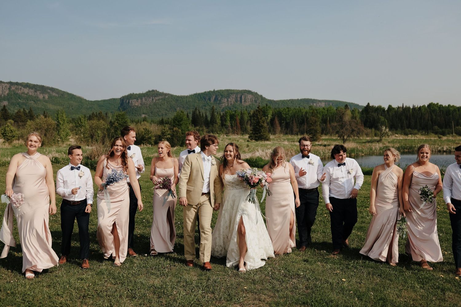 Newlyweds walk hand in hand through verdant vineyard at sunset.