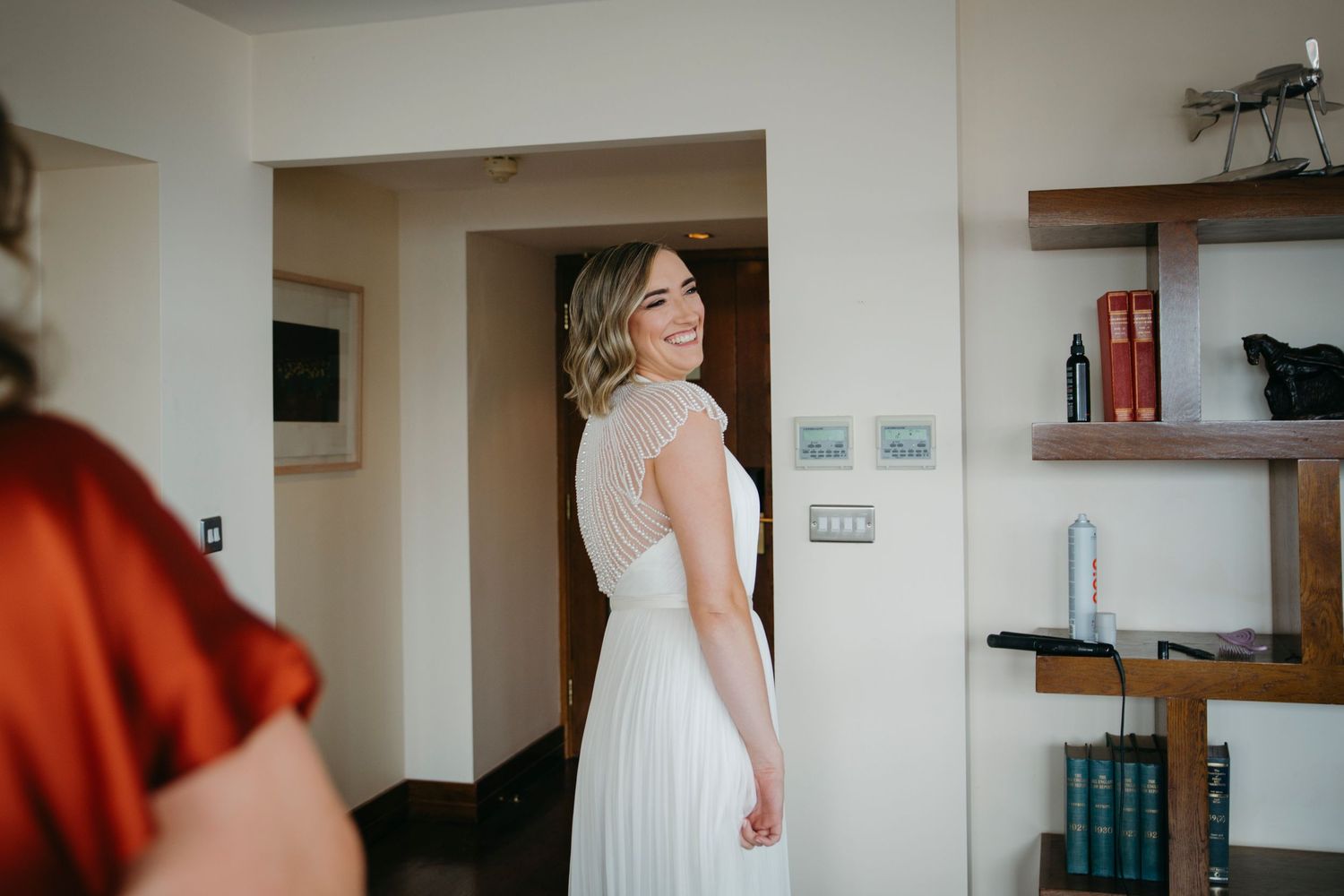 A bride in a detailed back wedding dress smiles over her shoulder.
