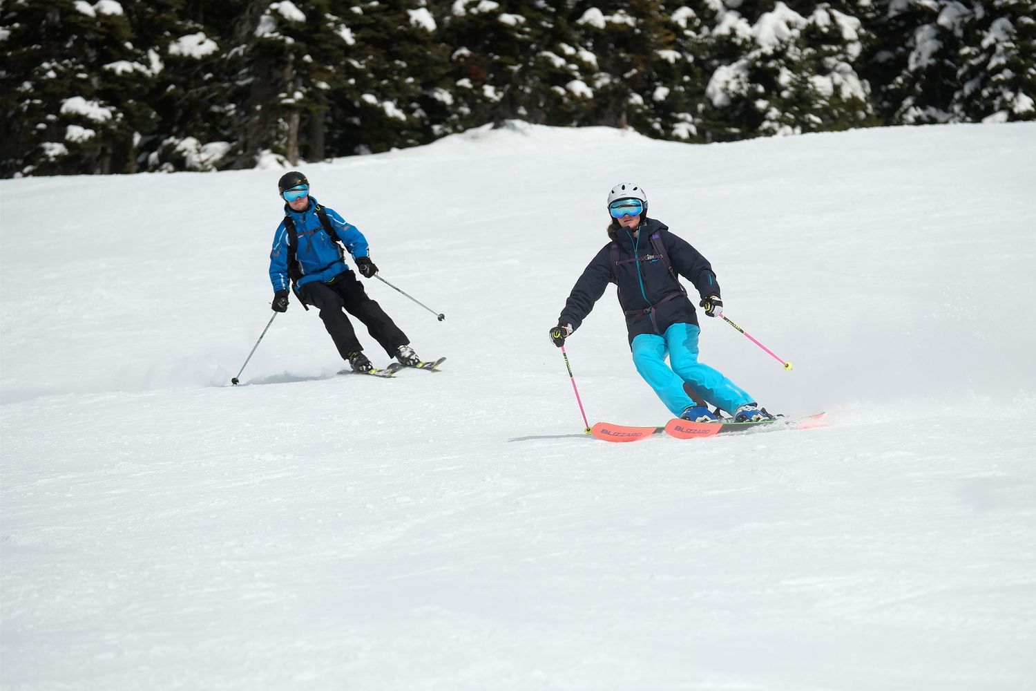 Two skiers in blue winter gear skiing down snowy slope together.
Whistler Blackcomb