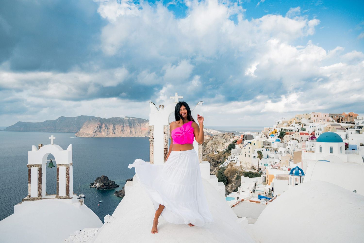 Beautiful view of Santorini's white architecture and blue domed churches against the Mediterranean Sea and cliffs.