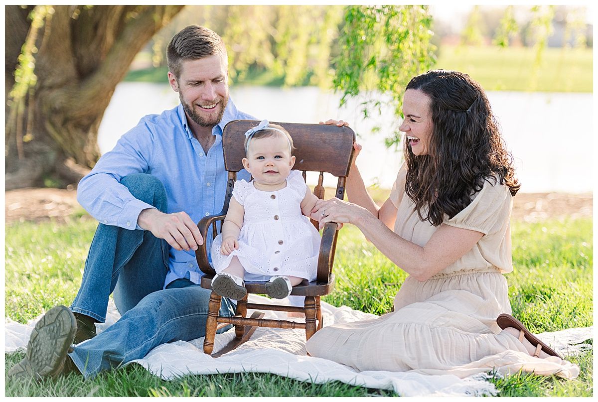 Baby girl in rocking chair during family portrait by lake at Coxhall Gardens