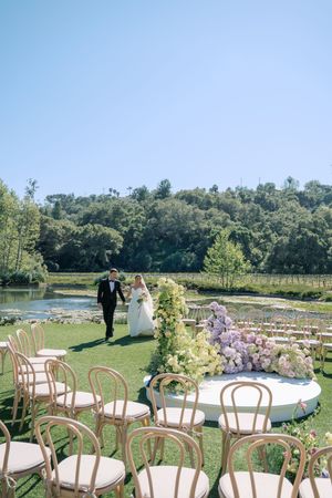 Garden wedding ceremony space with white chairs and curved seating arrangement overlooking a scenic lake view.