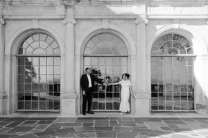 A series of arched windows and doorways along a white stone building facade with classical architectural details.