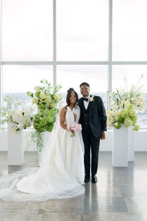 Wedding couple portrait in front of white floral arrangements in a modern bright venue.