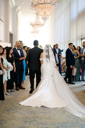 Bride and groom walking down the aisle at an elegant wedding ceremony with guests standing on both sides.