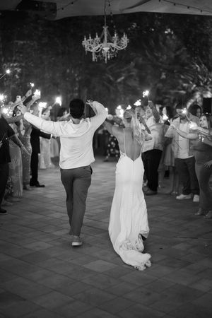 Black and white wedding reception celebration with guests holding sparklers in the evening.