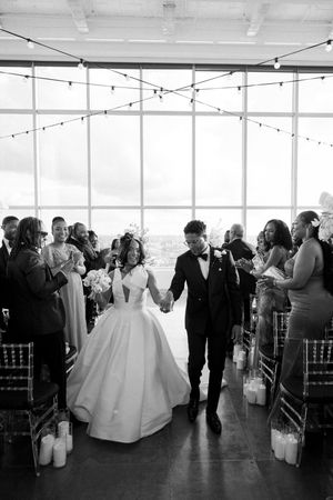 A wedding ceremony exit at a modern venue with string lights and floor-to-ceiling windows in black and white.