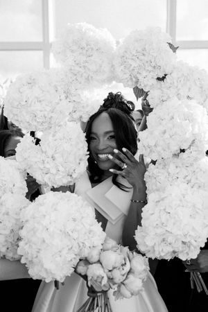 Black and white photo of bride holding large white hydrangea bouquet with butterflies scattered throughout.