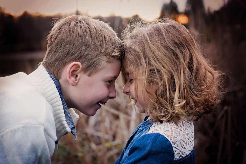 Intimate close-up moment between two children touching foreheads at sunset.
family photography