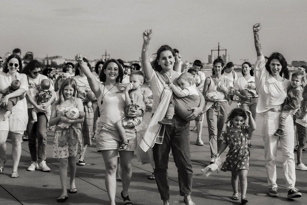 A joyful crowd of people marching and raising their arms in celebration in a black and white photo.