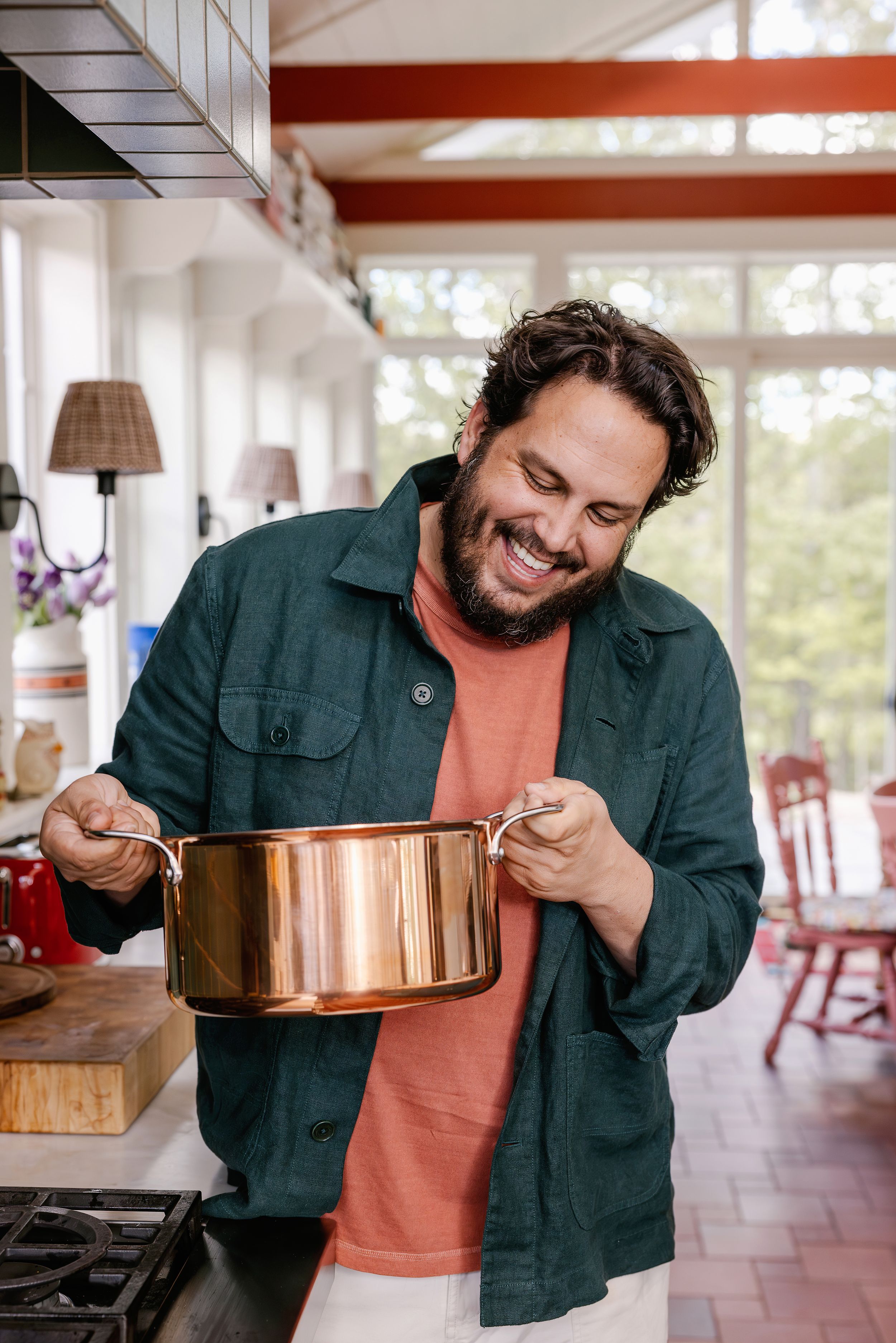 Cook and Best selling author Dan Pelosi holding a shiny All-Clad copper saucepan his bright, well-appointed kitchen.