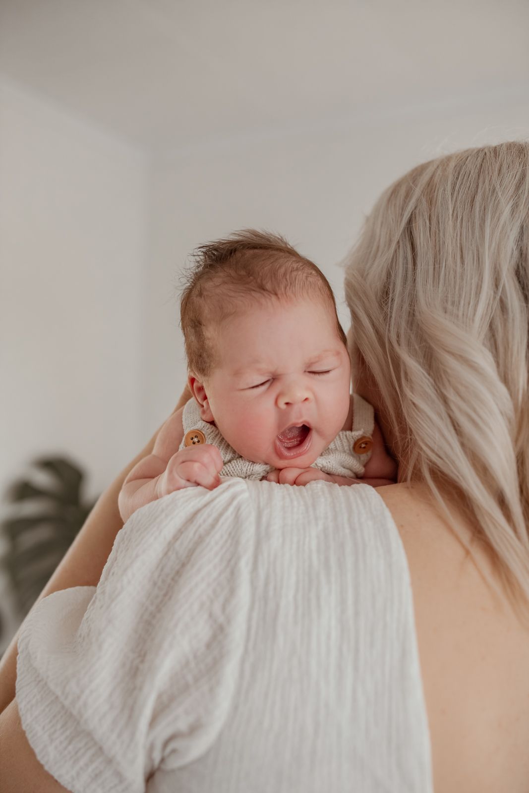 Parents cuddling their newborn baby during a cozy in-home lifestyle photography session in Westport.