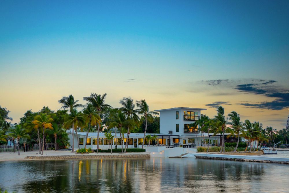 Luxurious waterfront home with palm trees and dock at sunset in the Florida Keys.