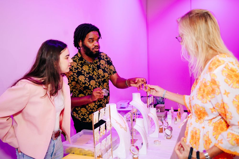Guests interacting at round tables during a pink-lit social gathering.
