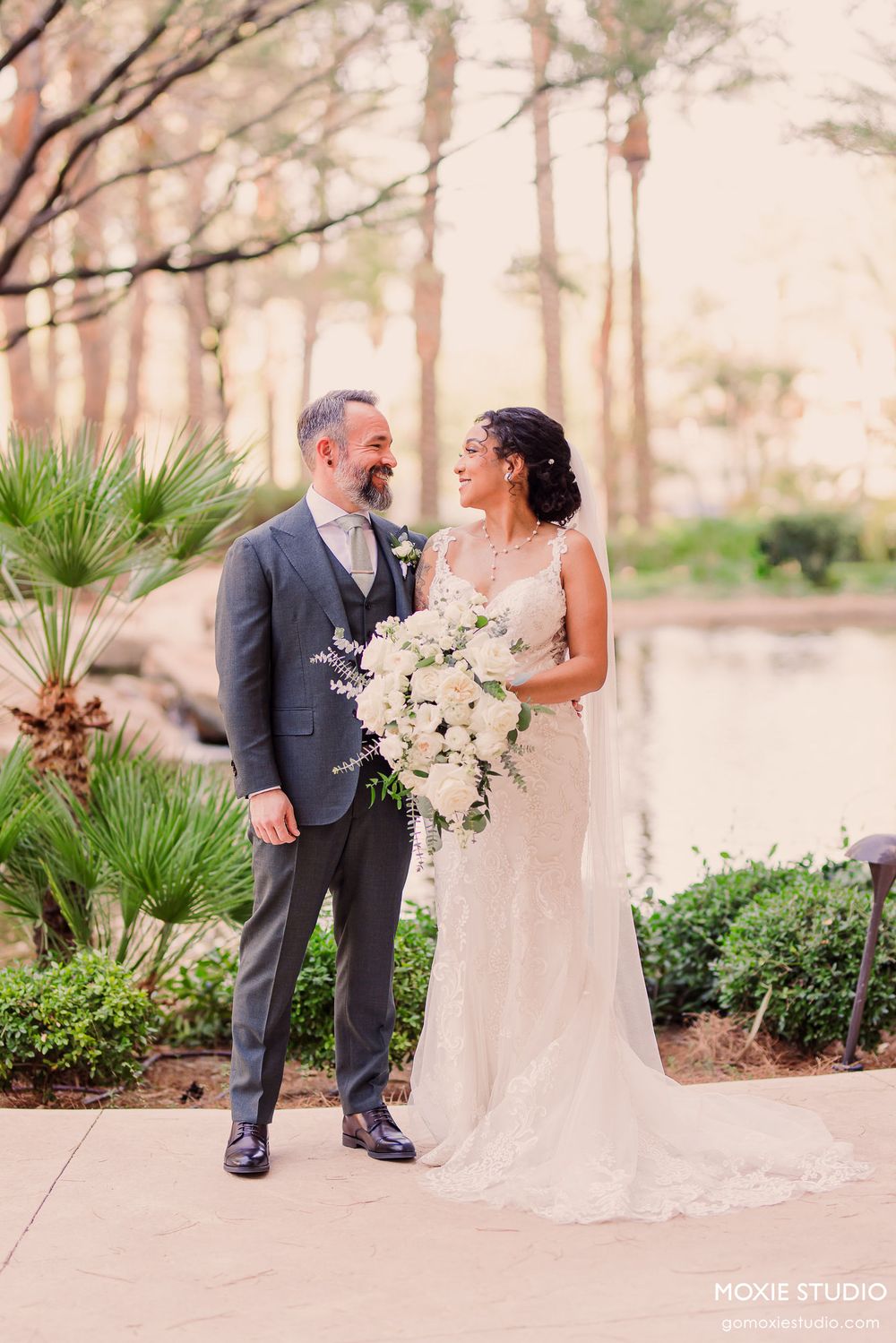 Wedding couple shares intimate moments in a lush garden setting with palm trees and greenery.
