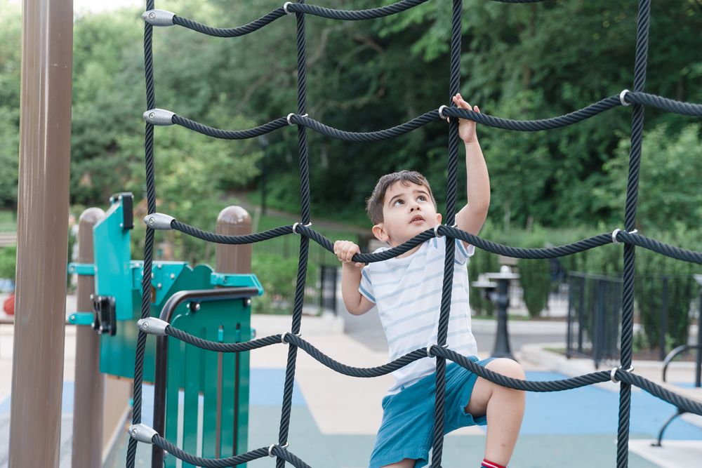 A young athlete performs a dynamic lateral movement exercise with cables in an outdoor fitness station.