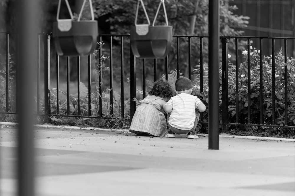 A black and white photograph shows people lounging and reading on benches in an outdoor plaza or courtyard area.