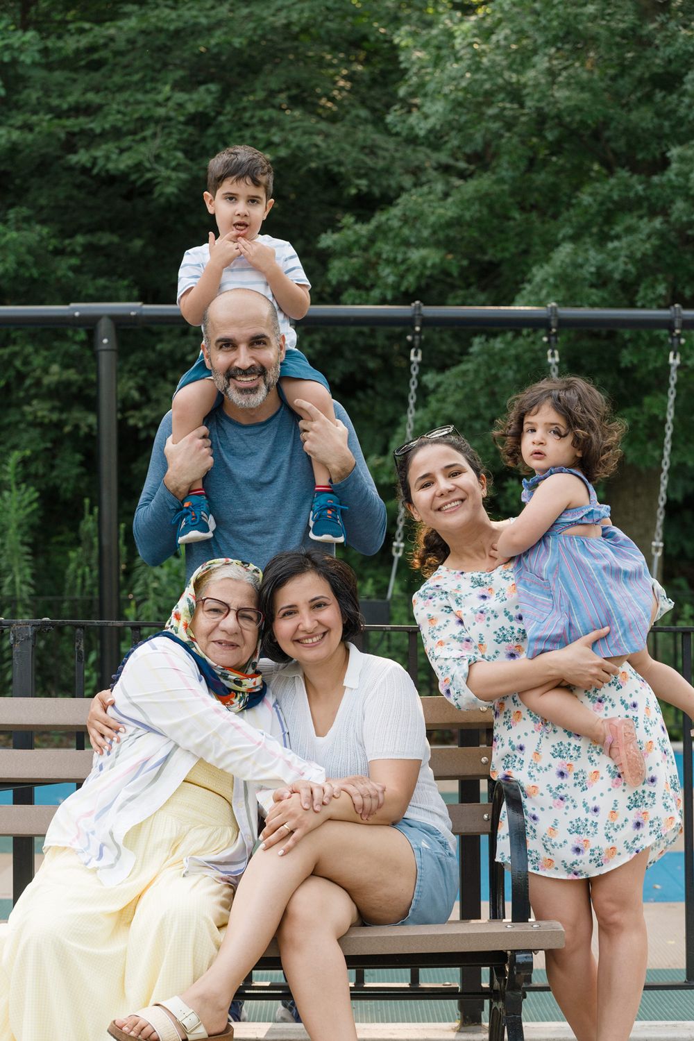 Happy group relaxing and enjoying time together on an outdoor wooden deck surrounded by lush green trees.