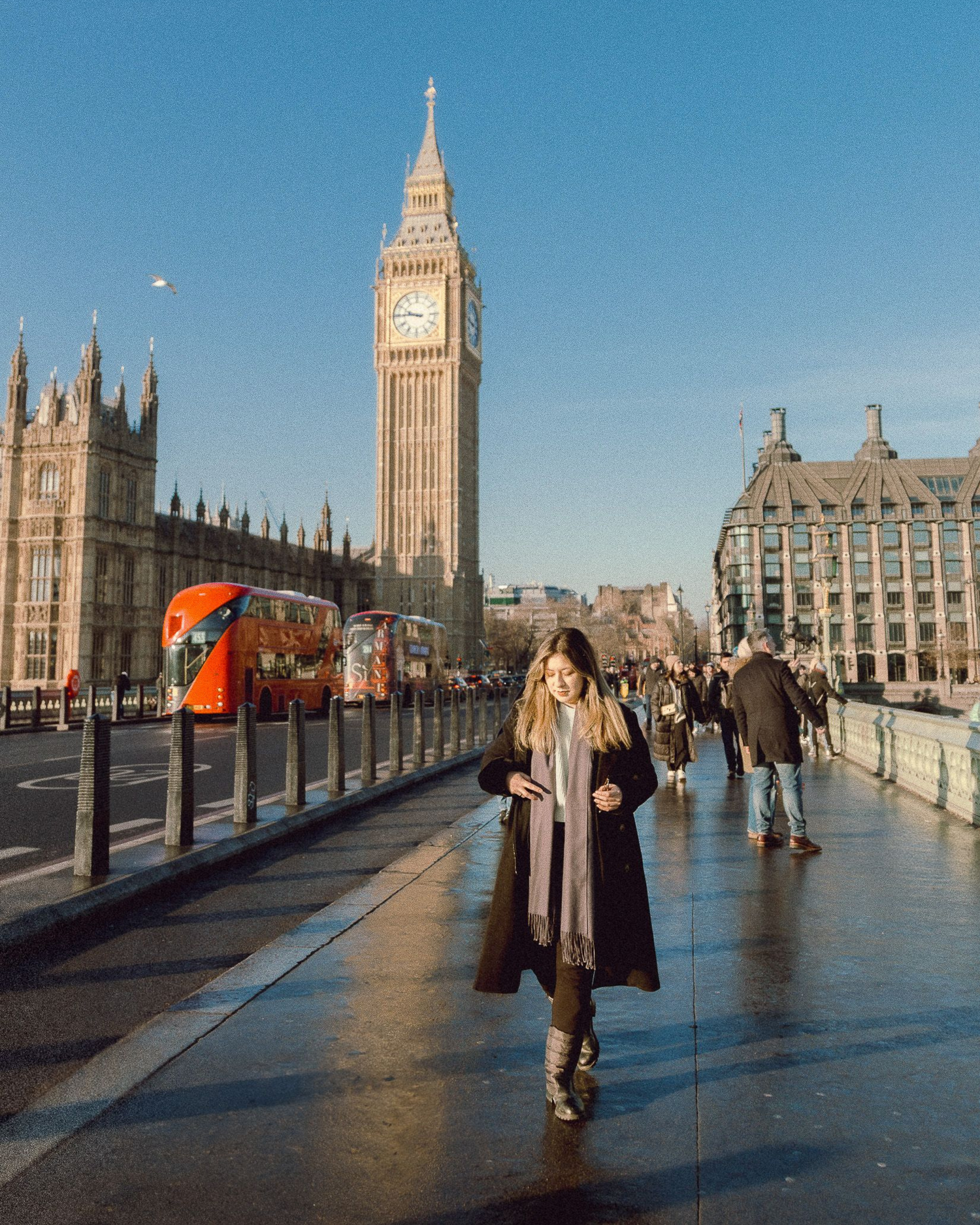 Tourist on Westminster Bridge with Big Ben and red double-decker bus in background.