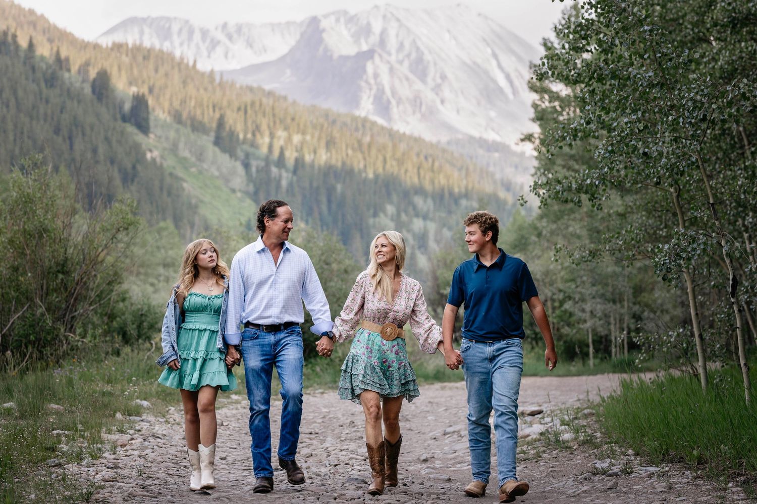 A sweet family walking hand in hand towards the photographer, Kelly Elizabeth