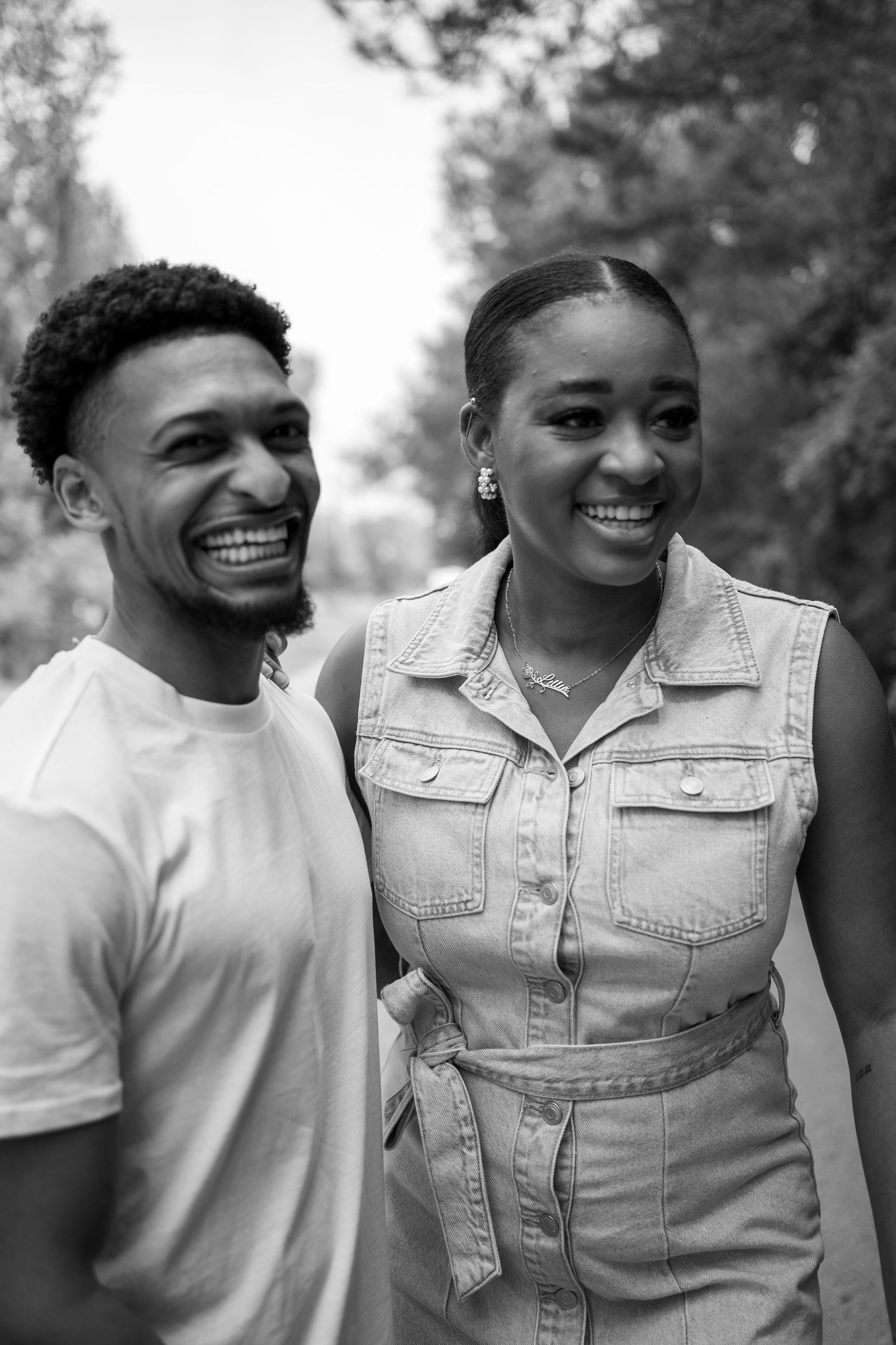 Black and white portrait of two people smiling together outdoors.