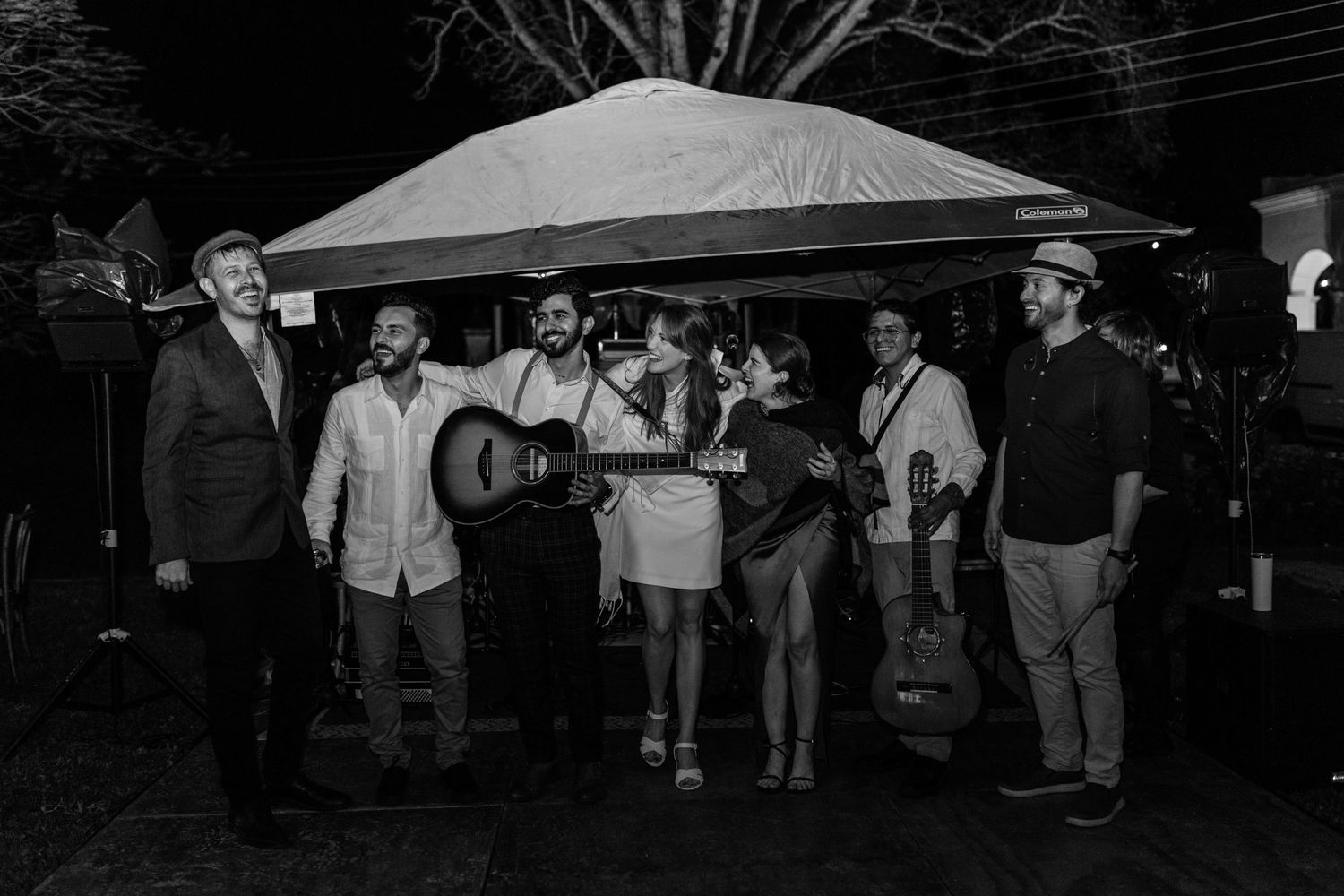 Black and white photo of wedding band performing under outdoor tent.