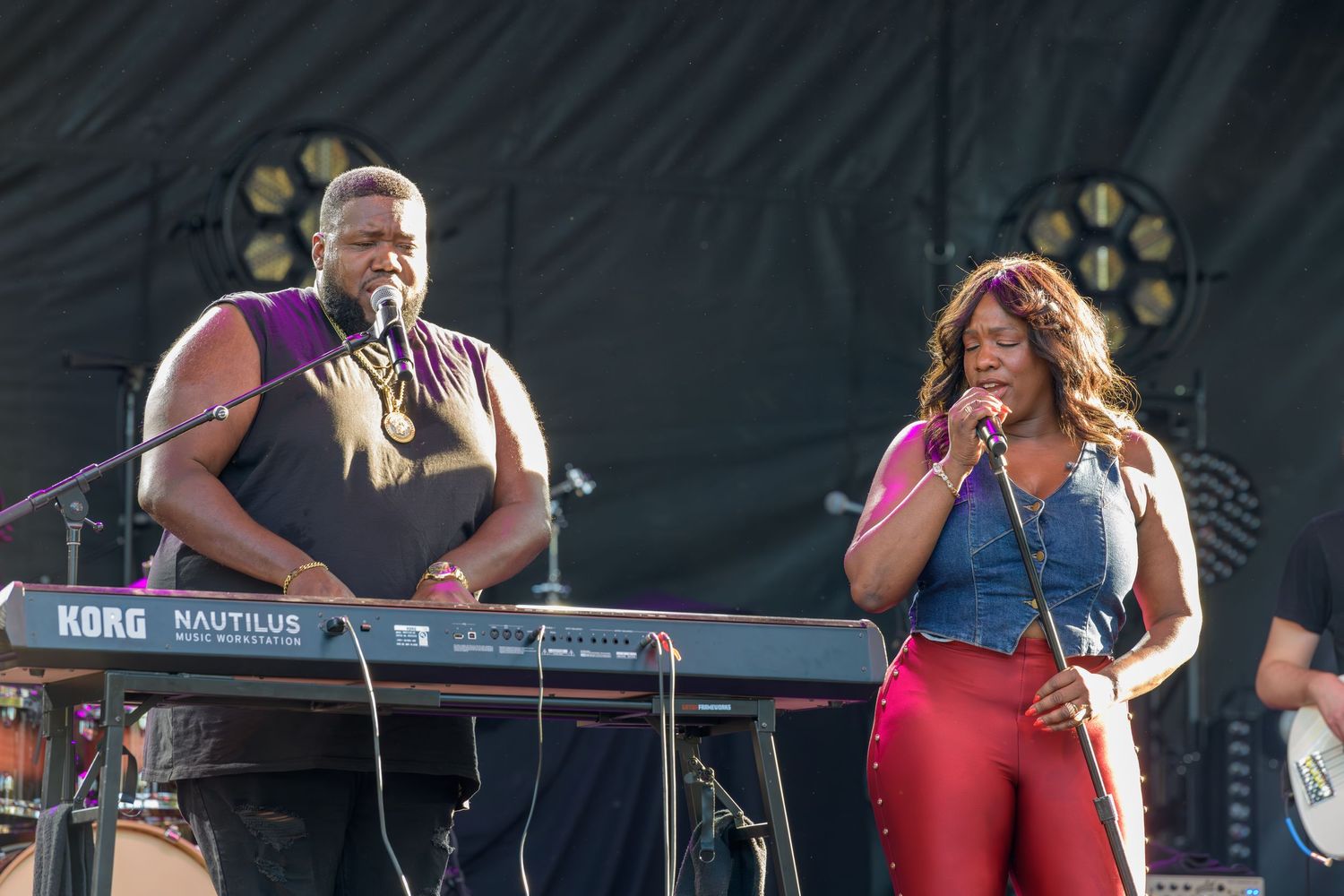 Musicians perform on stage with keyboards and microphone during a live concert performance.