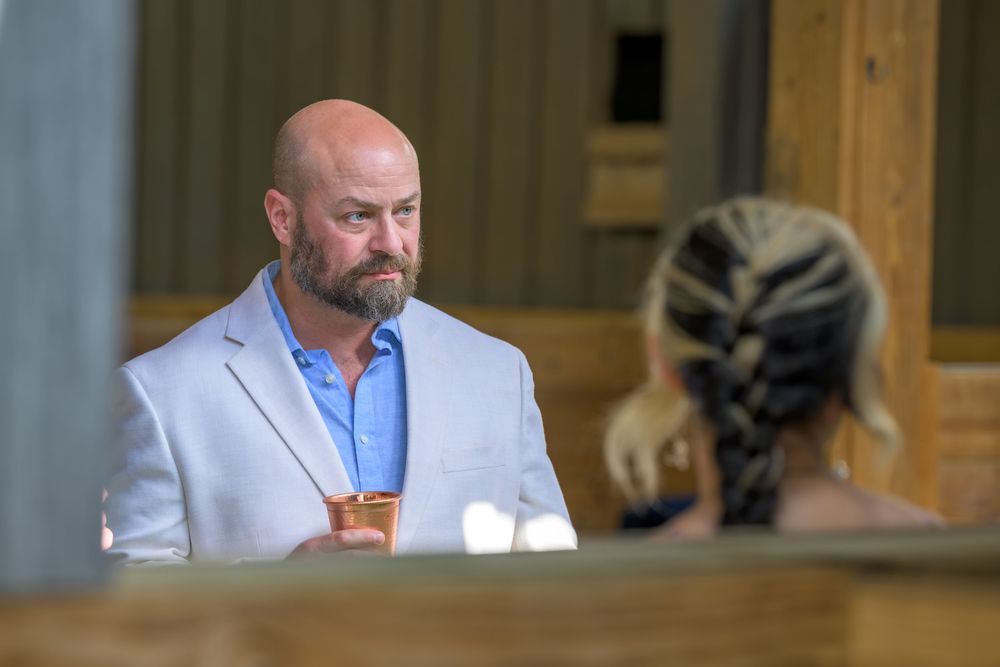A person in a light blue blazer sitting at a table during what appears to be a formal event.