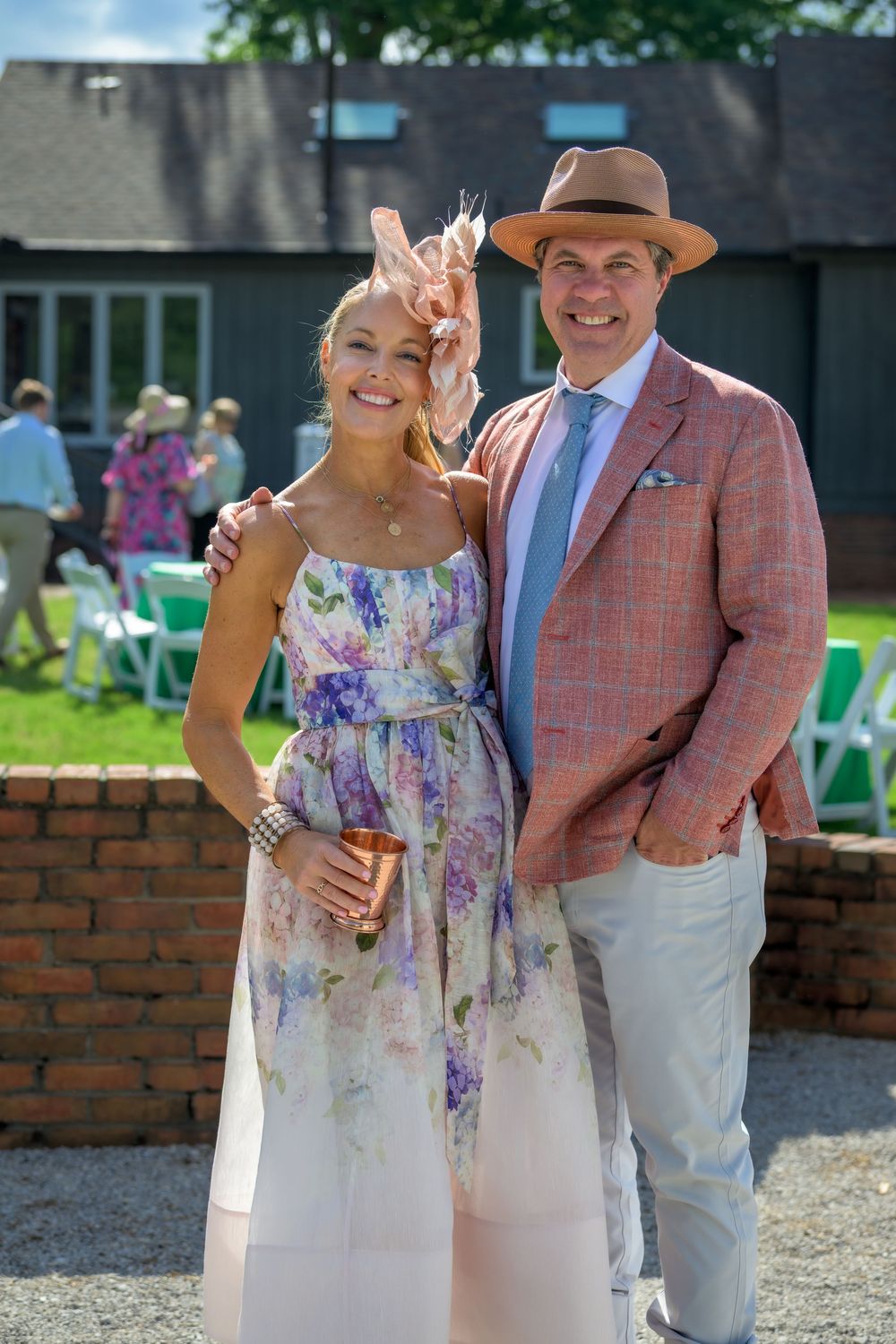 People dressed in summer garden party attire with floral dress and pink sport coat at outdoor event.