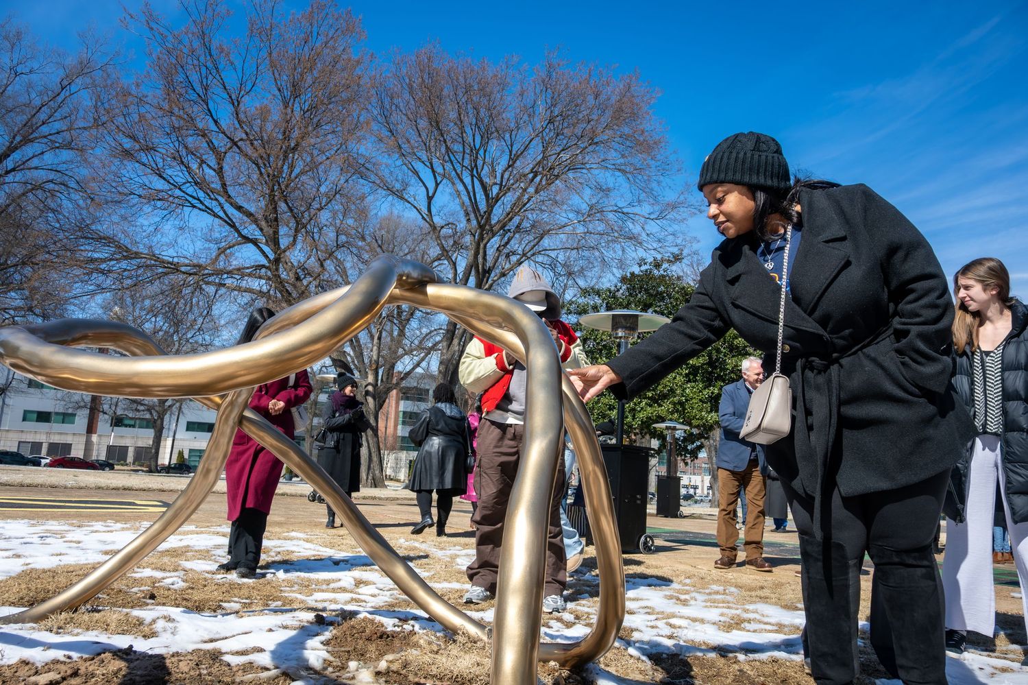 People enjoying outdoor fitness equipment at a public exercise park on a sunny winter day with snow on the ground.