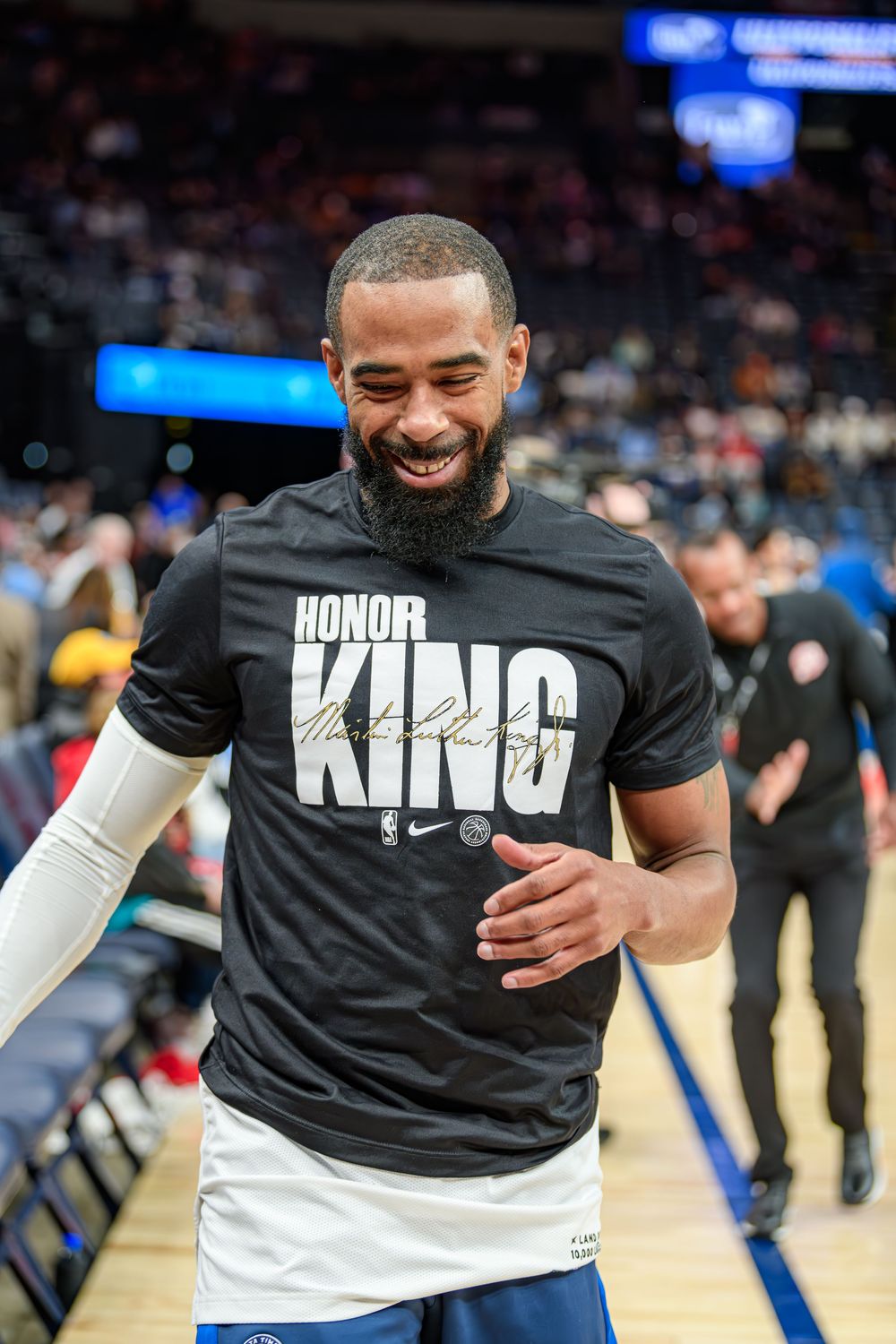 Basketball players wearing black 'KING' t-shirts warm up before a game on the court.