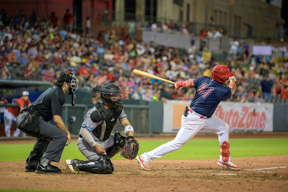 Baseball players collide at home plate during an intense play at the stadium.