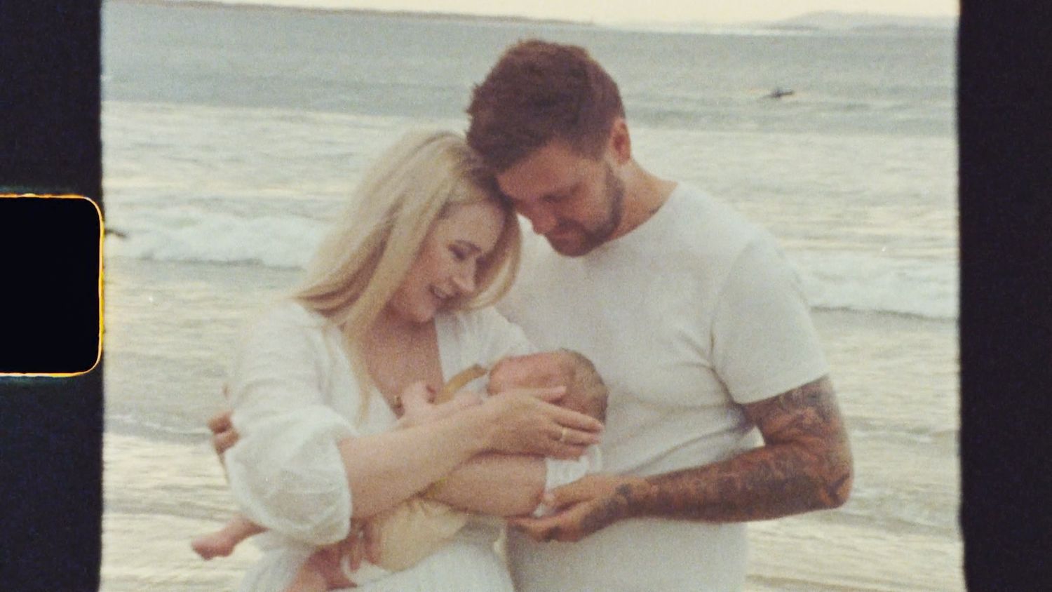 Still slide from Super 8 film of parents cuddling a newborn at the beach in Ocean Grove