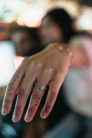 Close-up of an engagement ring with a diamond solitaire on a woman's hand in soft bokeh lighting.